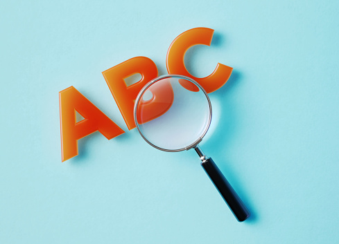 Magnifier and ABC text on aquamarine background. Horizontal composition with copy space.