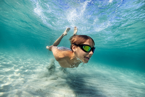 Little boy swimming underwater in the sea. The boy is enjoying the summer vacations.\nCanon R5