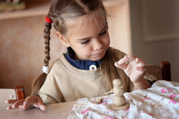 A child engages in crafting clay dinosaurs, focusing intently on the details of the figures.