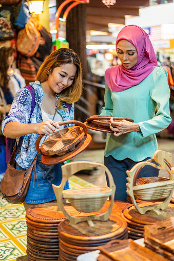 Attractive Asian Millennial Friends shopping in a local Bazaar. \n\nLocation: Malaysia, Kuala Lumpur\n\niStockalypse Kuala Lumpur