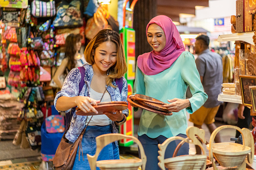 Attractive Asian Millennial Friends shopping in a local Bazaar. \n\nLocation: Malaysia, Kuala Lumpur\n\niStockalypse Kuala Lumpur