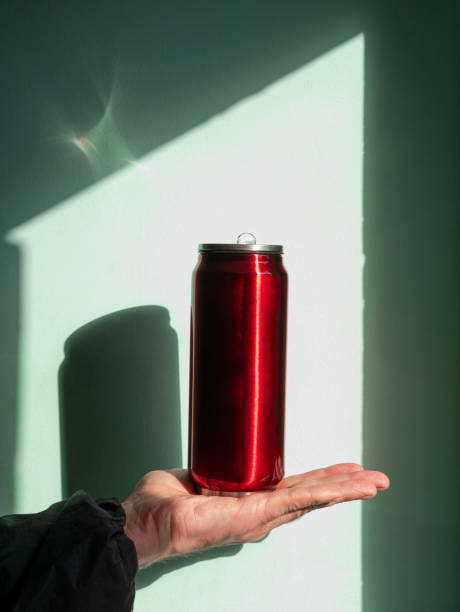 istock Red thermo can bottle in male hands against wall with harsh shadow.Hot tea coffee drinking in cold autumn winter weather 1348045331