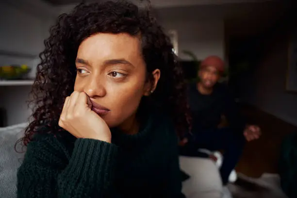 Mixed race female ignoring black boyfriend while on the sofa in modern apartment