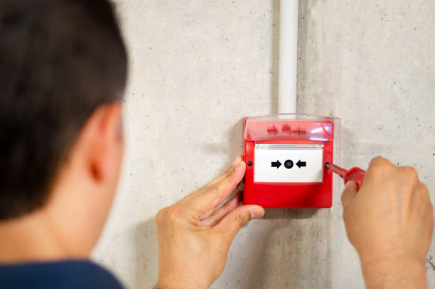 installing fire alarm A back view of electrician installing fire alarm system fire alarm photos stock pictures, royalty-free photos & images