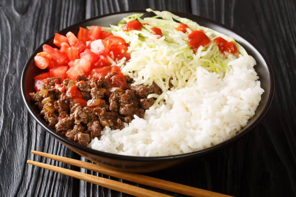 Japanese taco rice with ground beef, vegetables, cheese and sauce close-up in a bowl. horizontal
