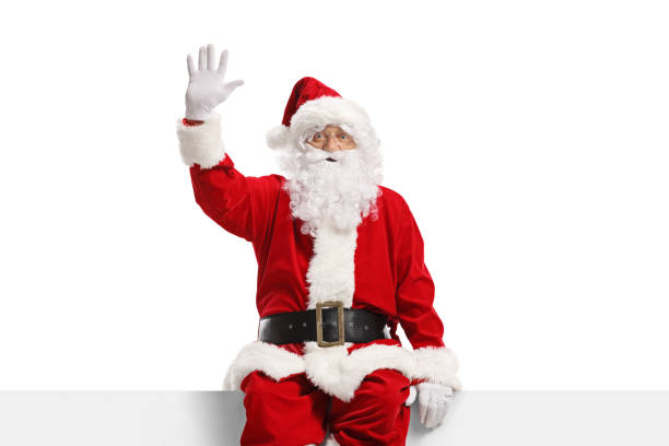 istock Cheerful santa claus sitting on a panel and waving 1348050704