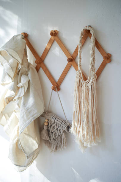 istock Decor items hang on a white wall on a wooden hanger. Macrame , towels. Rustic style 1348050778