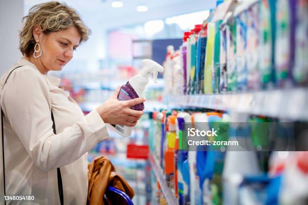 Woman Choosing Domestic Cleaning Product By The Supermarket Shelf Stock Photo - Download Image Now