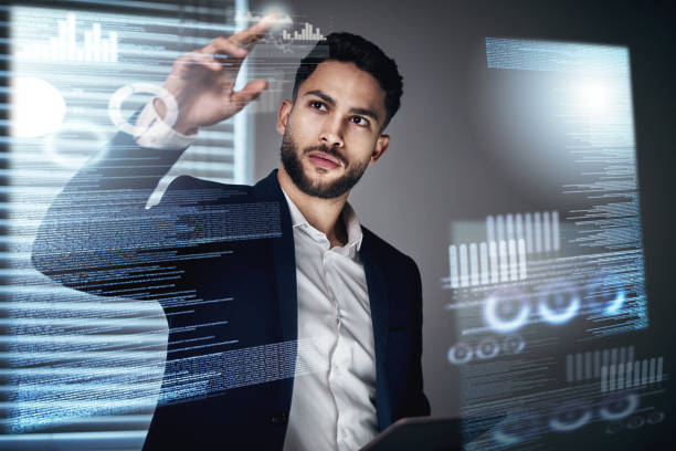 Shot of a handsome young businessman standing alone in the office at night and using an interactive screen All the information is at my fingertips fx stock pictures, royalty-free photos & images