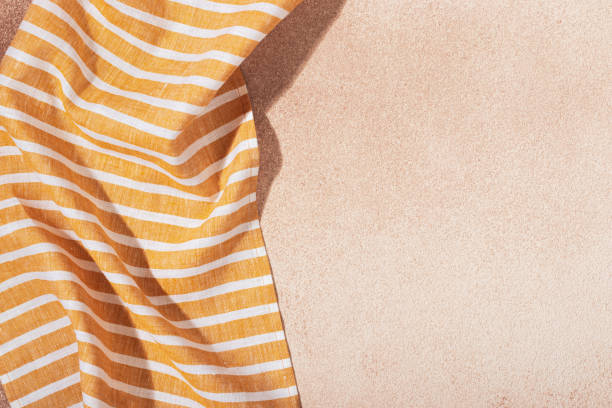 istock Striped textile yellow serving napkin on beige plastered backdrop 1348055221