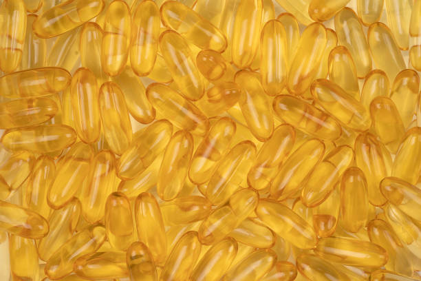 золотая треска печень рыбий жир капсула, витамин d на фоне - gel effect capsule fish oil pill стоковые фото и изображения