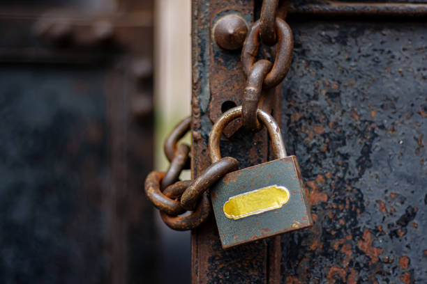istock Hinged lock closed on the chain hangs on the old metal gate. 1348056583