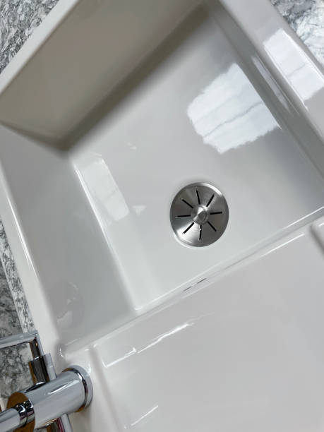 Stock photo showing an elevated view of a modern rectangular single bowl kitchen sink with drainage board with stainless steel tap, white ceramic Belfast sink with grey and white patterned granite worktop countertop. imagen de primer plano del fregadero de cocina rectangular moderno de un solo tazón con tablero de drenaje con grifo de acero inoxidable, fregadero belfast de cerámica blanca con encimera de granito estampado gris y blanco, vista elevada