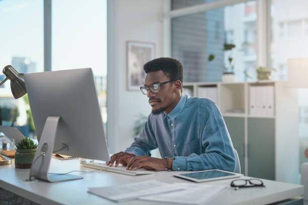 istock Shot of a young businessman using a computer at his desk in a modern office 1348066501