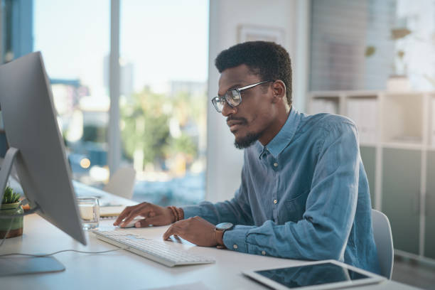 istock Shot of a young businessman using a computer at his desk in a modern office 1348066503