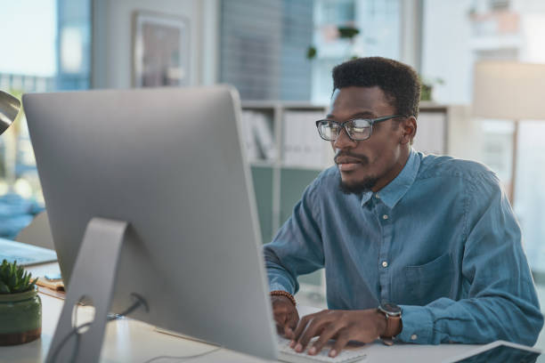 istock Shot of a young businessman using a computer at his desk in a modern office 1348066512