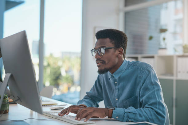 istock Shot of a young businessman using a computer at his desk in a modern office 1348066515