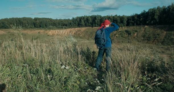 istock Hiker walks with a backpack in a large, sandy quarry at sunset 1348066582