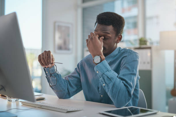 istock Shot of a young businessman looking stressed while using a computer at his desk in a modern office 1348068680