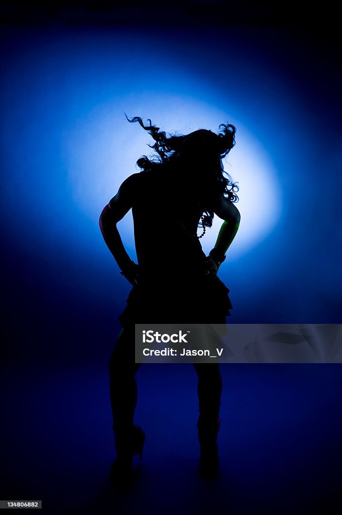 Dancer Silhouette A silhouetted dancer in front of a blue spotlight (Some motion blur in hair and feet) Dancing Stock Photo