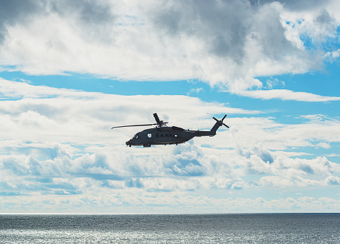 Twin engine navy helicopter flying over the Atlantic.