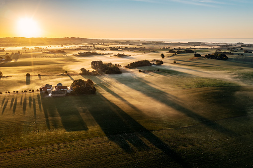 Drone view of over the island of Moen in Denmark as the sun burns off the early morning fog. Colour, horizontal with some copy space.