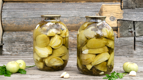 Pickled green tomatoes made from fresh organic tomatoes. Wooden background. Home canning concept.