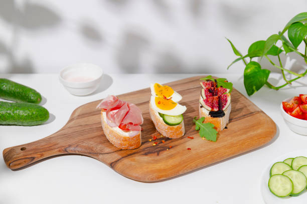 istock Toasts with cream cheese, prosciutto, vegetables and eggs on a wooden cutting board 1348079167