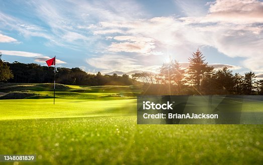 istock Golf course putting green with flag at sunset 1348081839