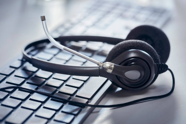 auriculares en el fondo del teclado de una computadora de escritorio - centro de llamadas fotografías e imágenes de stock