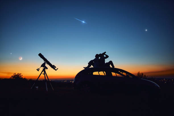 istock Couple stargazing together with a astronomical telescope. 1348081922