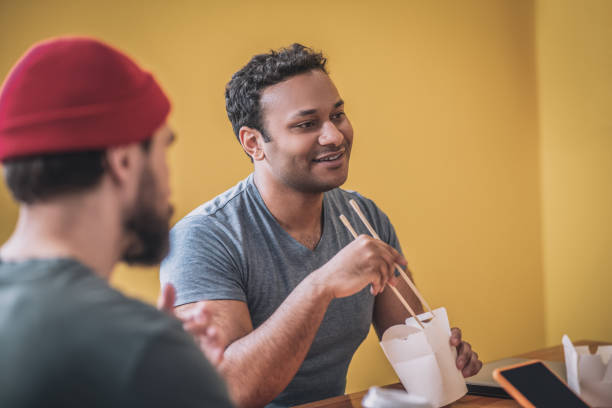 istock Dark-skinned smiling guy eating thai food 1348082428