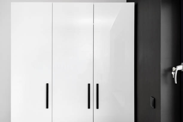 istock Large and high wardrobe in the bedroom with white fronts and black handles. 1348082489