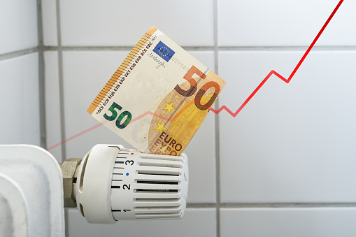 Rising curve of increasing costs for heat and energy, problem for home budgets symbolized by a banknote in the thermostat of a heating radiator, finance and money concept, copy space, selected focus