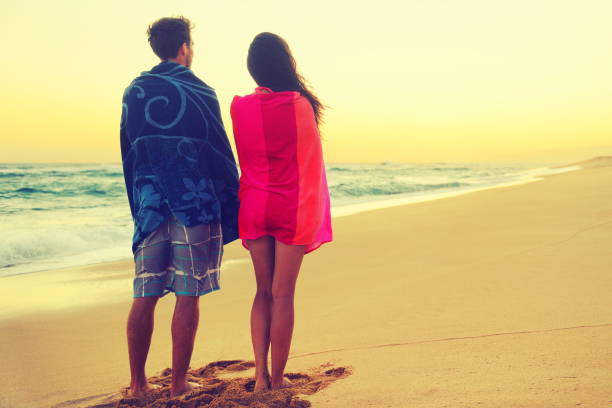 istock Romantic couple bathing with towels on beach sunset 1348086212