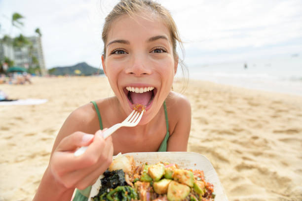 ビーチでサラダ健康的な食事を食べる面白い女性 - prepared ahi ストックフォトと画像