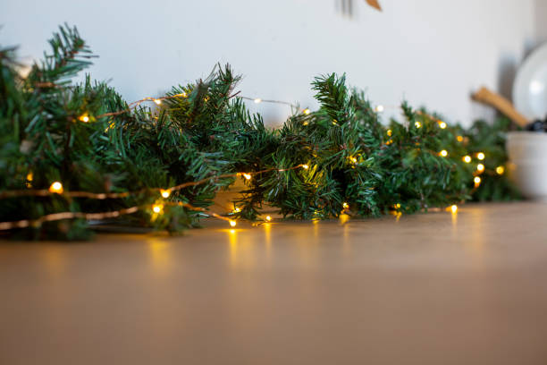 light bulbs in coniferous branches on kitchen table. christmas atmosphere.home decor for celebration stock photo
