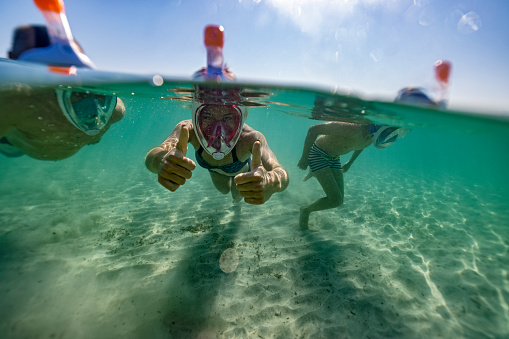 Senior man playing underwater with his grandchildren. They are enjoying the summer vacations.\nCanon R5