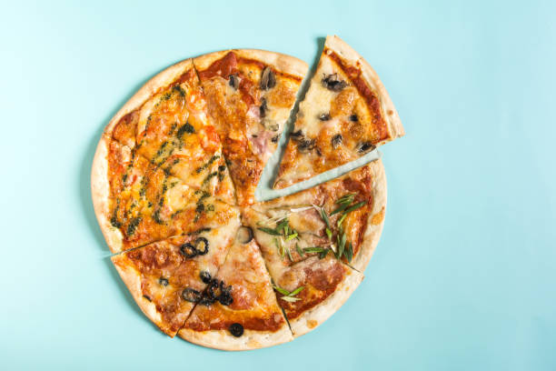 istock Fresh pizza with four flavors on a thin dough on a colored background top view. Pizza on thin dough close-up 1348087739