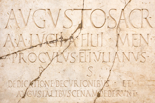 Latin inscription on an ancient cracked marble slab in Rome.