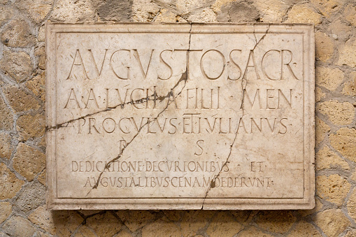 Latin inscription on an ancient cracked marble slab in Rome.