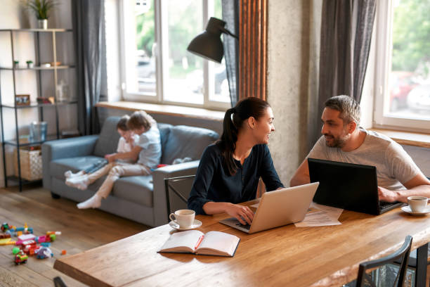 istock Smiling parents work online on laptops from home 1348091176
