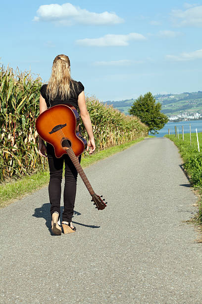 istock Guitarist walking down country road 134809390