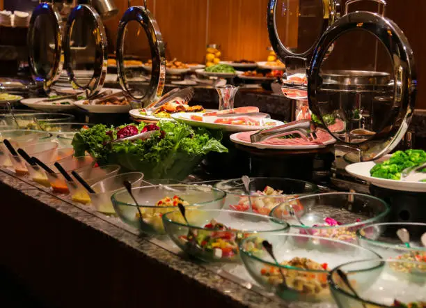 Photo of Salad bar with stainless steel tongs in round chafer server and glass bowls at bbq restaurant