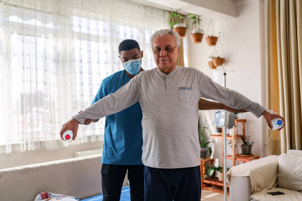 istock Old man training with physiotherapist using water bottles at home. 1348096428
