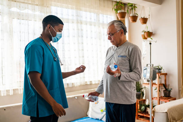 istock Old man training with physiotherapist using water bottles at home. 1348096516