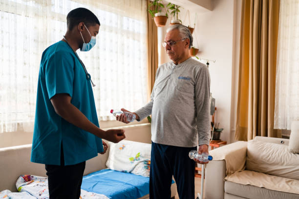 istock Old man training with physiotherapist using water bottles at home. 1348096524