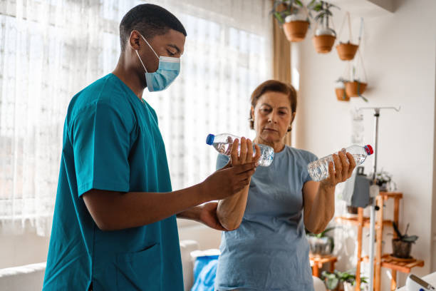 istock Old woman training with physiotherapist using water bottles at home. 1348097718