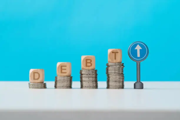 Photo of Word debt on heap of coins