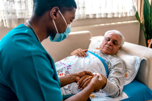 male nurse attaching IV drip on patient stock photo